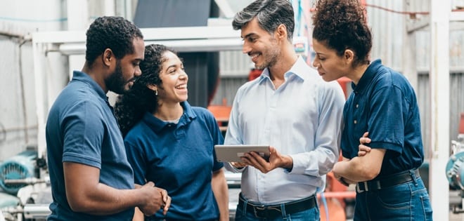 Two men and two women are huddled around a tablet
