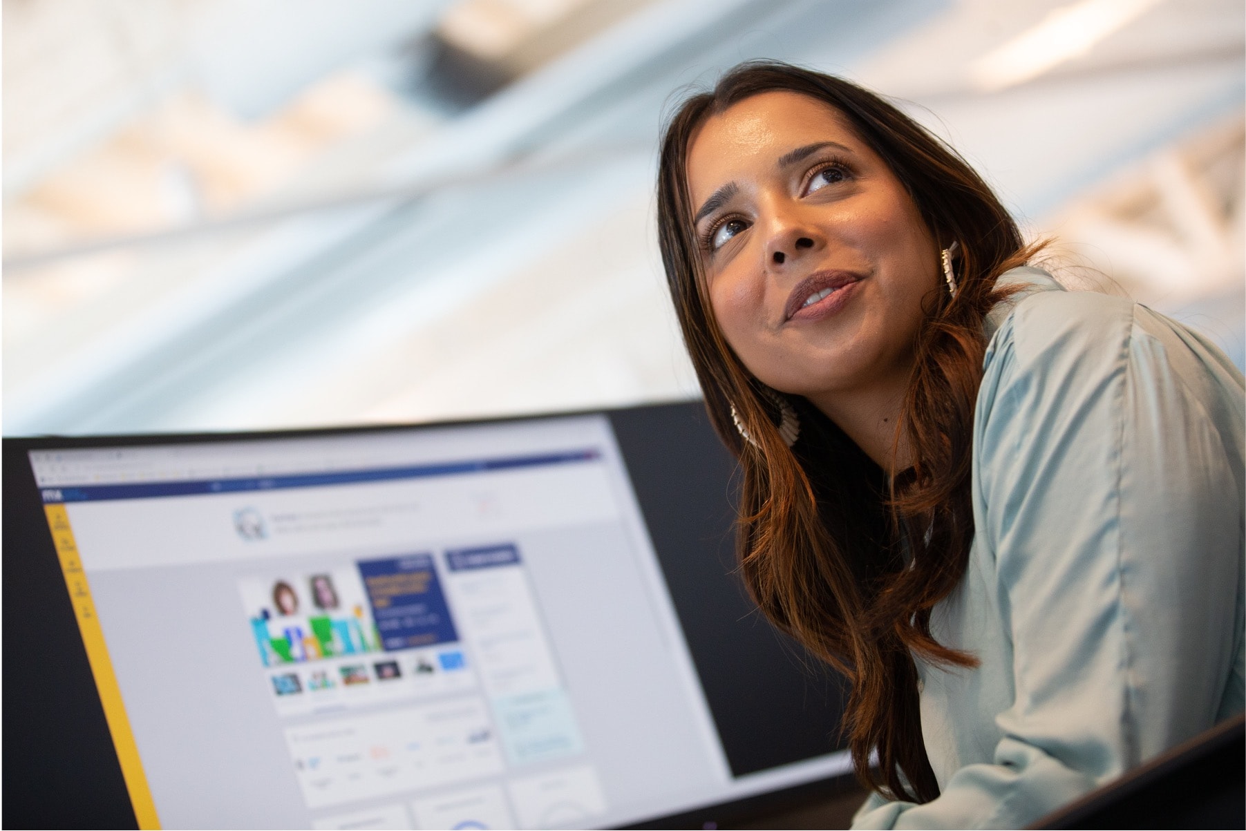 A woman sitting at a desk, turning away from a computer monitor