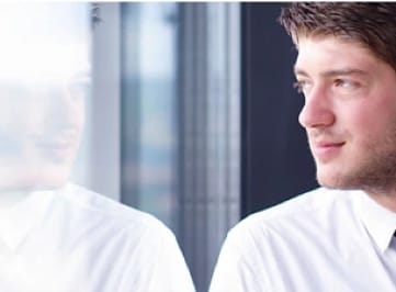 Young businessman with slight beard looking out window