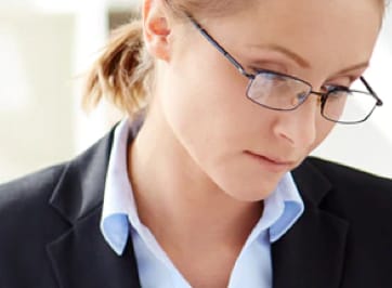 A businesswoman wearing glasses looking down