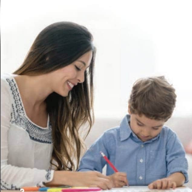 Mother smiling while watching her son writing on paper