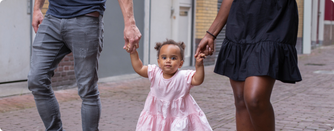 Family holding hands of little girl in pink