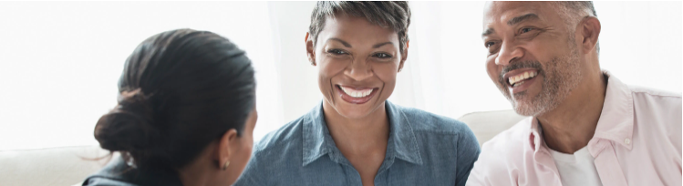 male and female smiling side by side talking to woman across from them in black blazer top