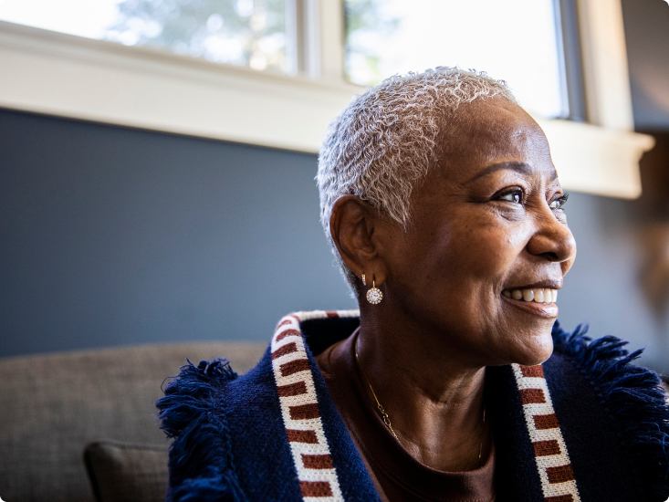 A woman with short gray hair looking to the side and smiling