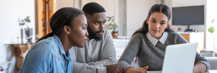 A woman explaining something on a laptop screen to a man and a woman