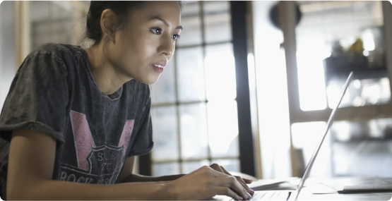 A woman focused on a laptop screen typing in a home office