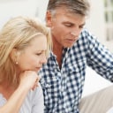 Woman and man, sitting on a couch, looking at a document