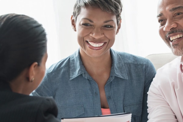 A man and a woman smiling sitting across from another woman 