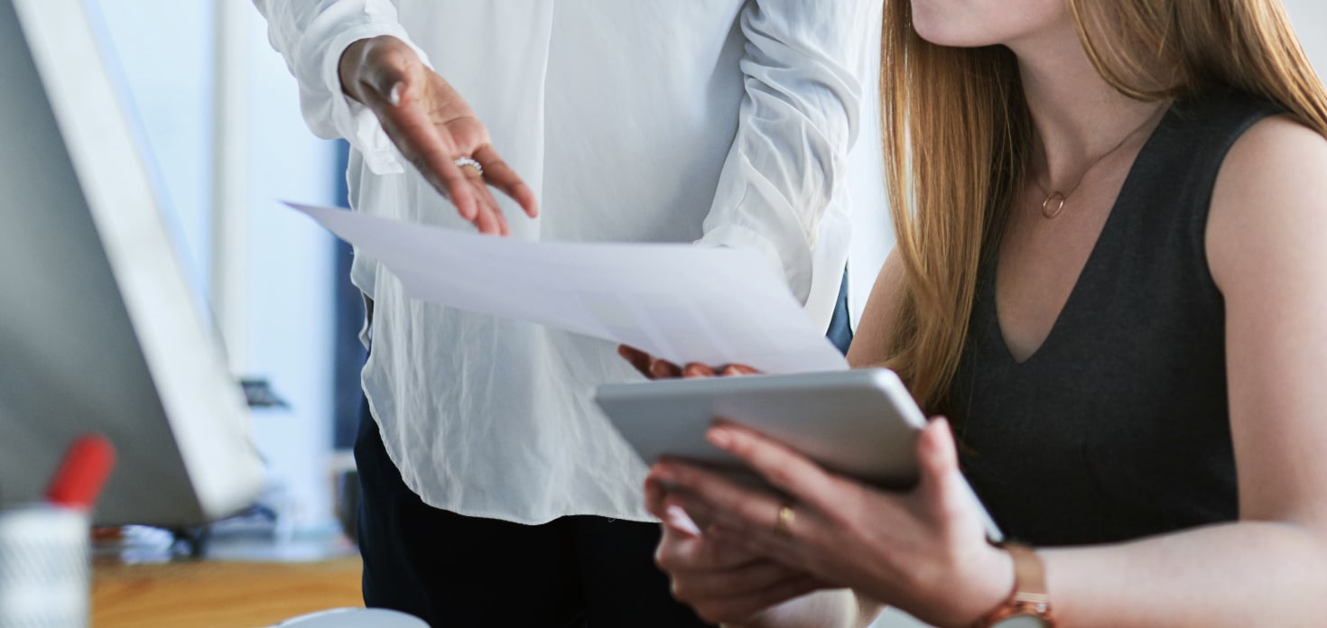 woman in black top talking to a employee in white long sleeve about results on a paper