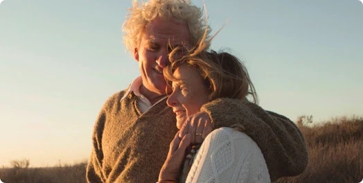 A man with his arm around a woman looking at a sunset