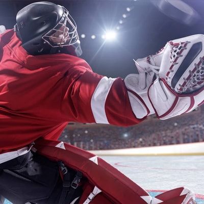 A hockey goalie stretching to block a puck from going into the goal