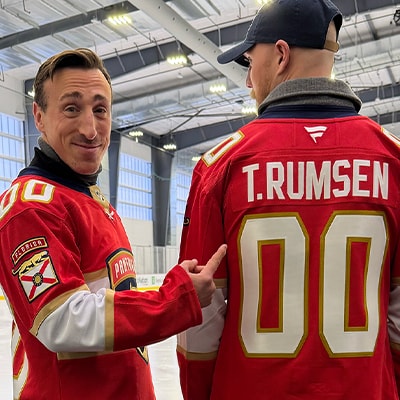 T. Rumsen, a professional hockey player, pointing to a jersey with his name on it