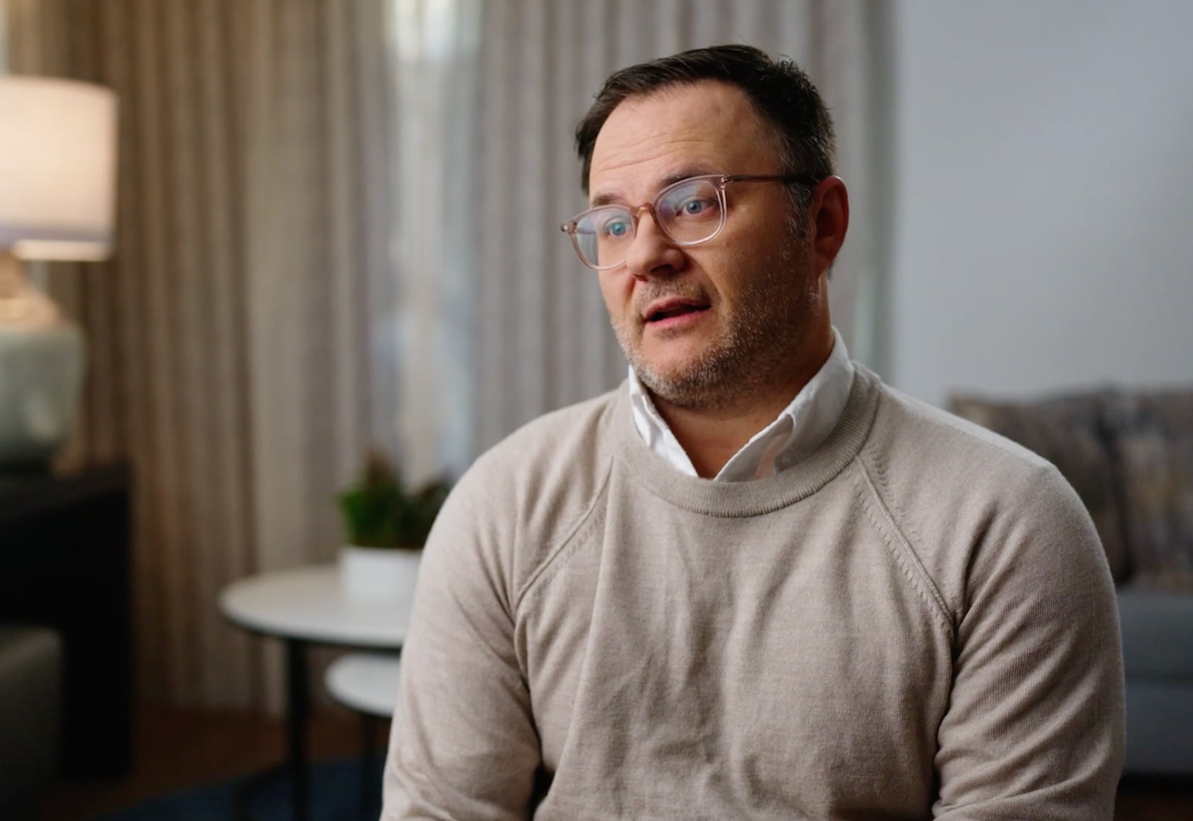 Man in beige sweater looking at camera
