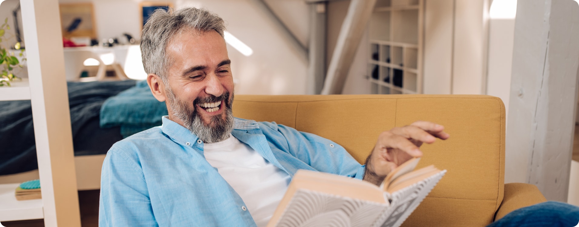Male with blue button up smiling and reading a book.