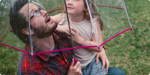 A man and a young girl looking up through an umbrella