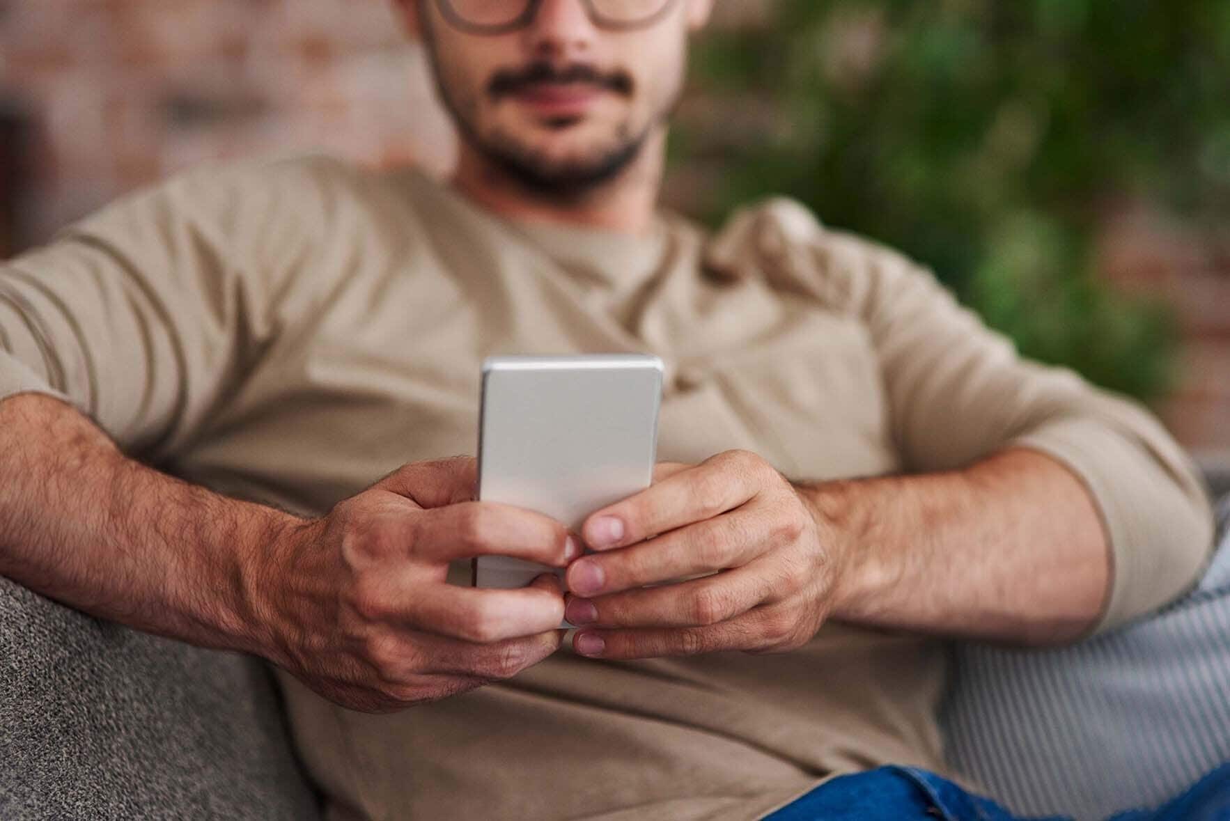 Man sitting on a chair typing on cell phone