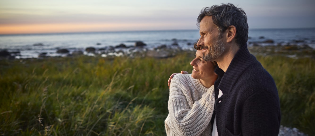 Couple standing on the shoreline looking out to the water