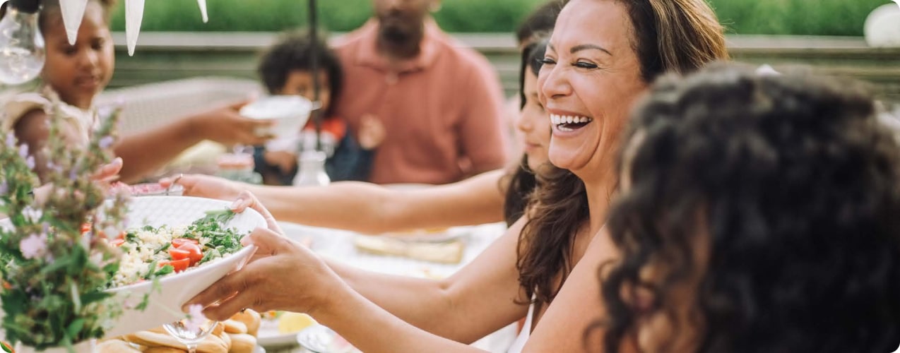 Group of people passing food around a table.