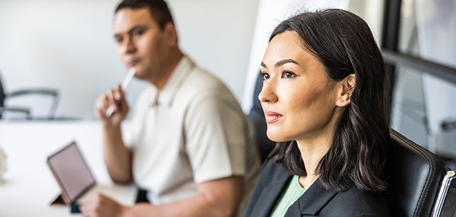business professionals sitting around a conference table collaborating in a conference room surrounded by windows