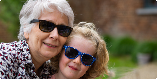 Grandmother and granddaughter wearing sunglasses smiling
